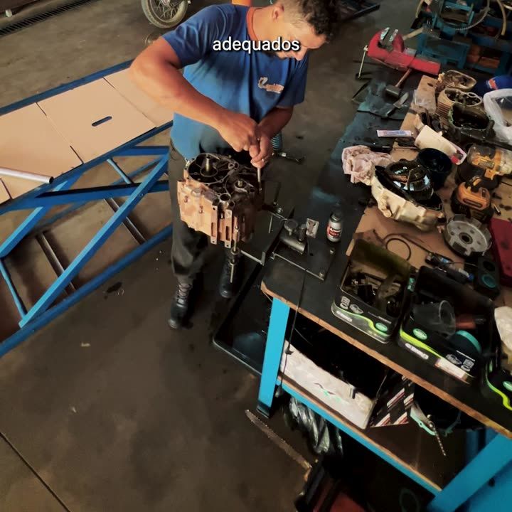 Mecânico desmontando motor na bancada da oficina